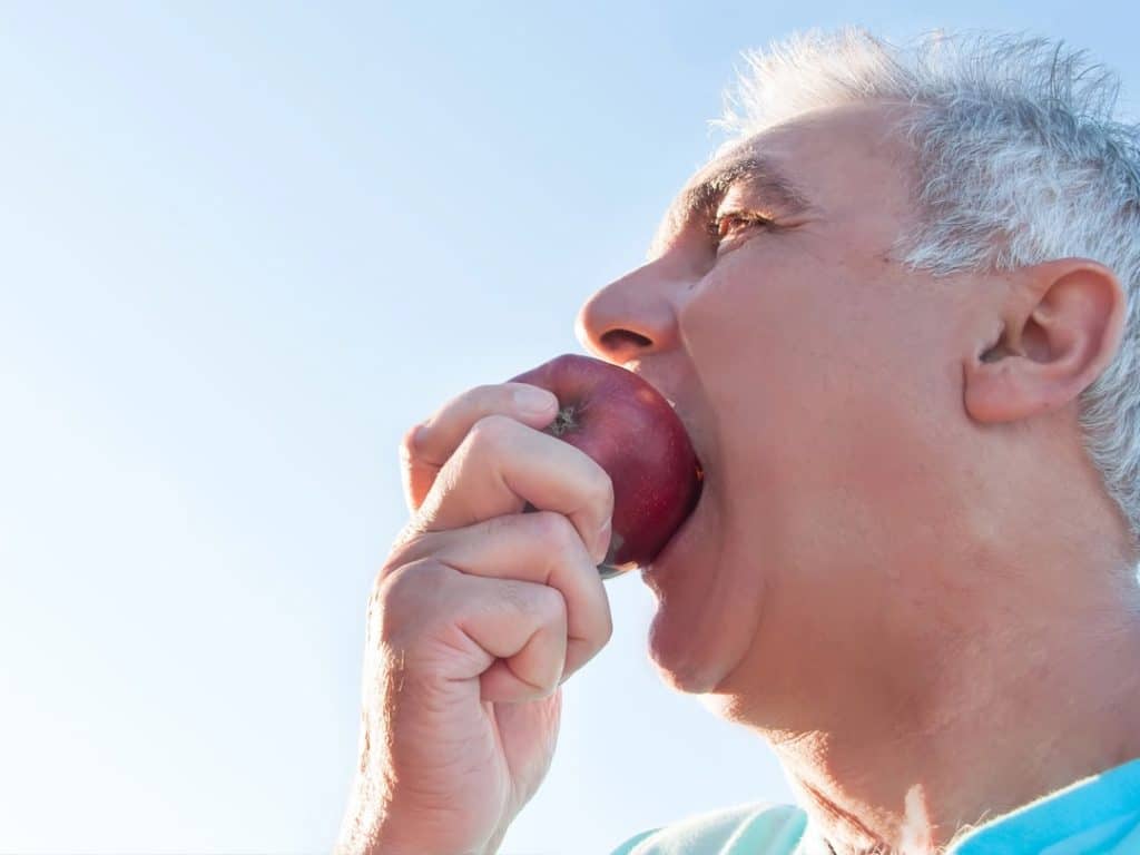 Man chewing on an apple with dental crowns