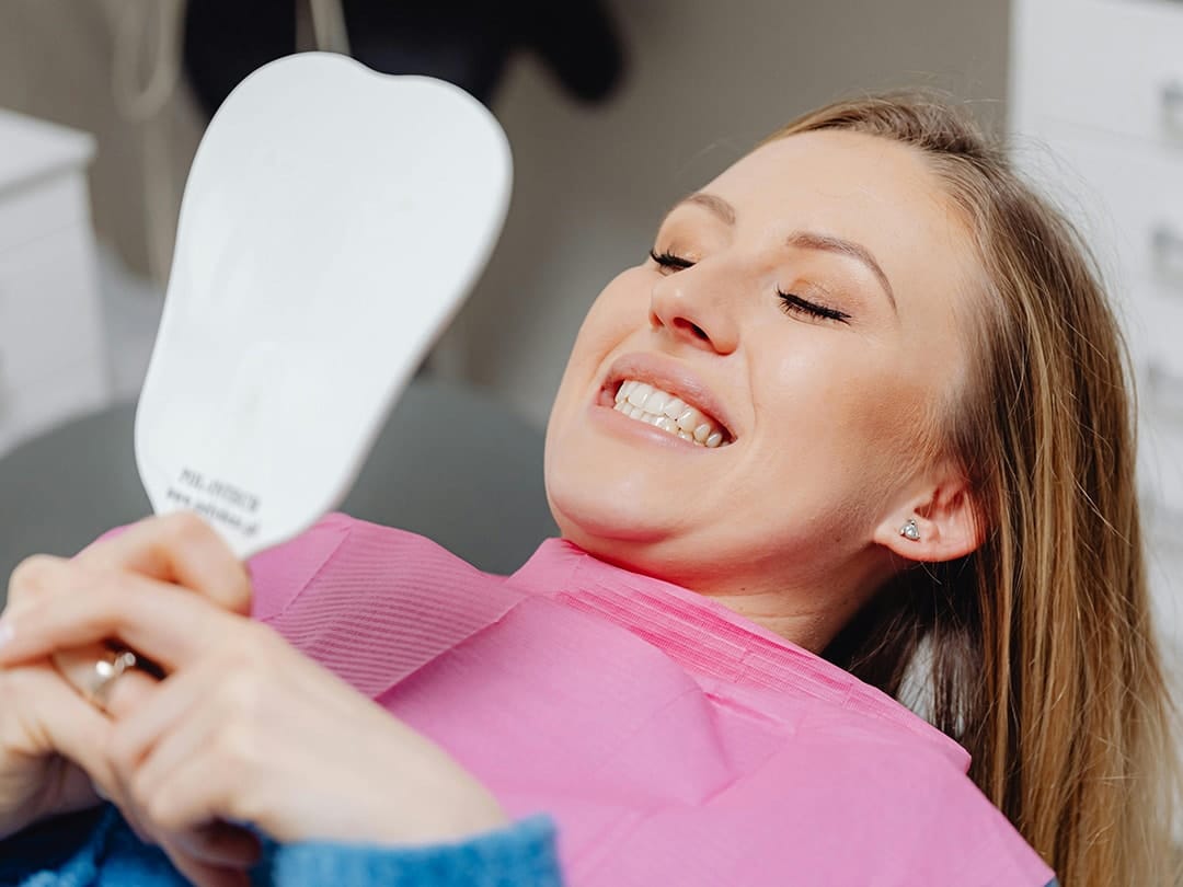 Patient sat in dentist chair with perfect crowns and bridges smiling