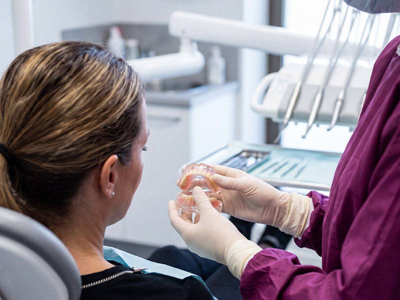 Dentist showing patient denture mould as patient is sat in chair